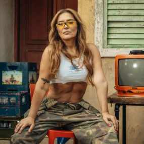 Stylish woman posing with a vintage TV, exuding a retro streetwear vibe outdoors.
